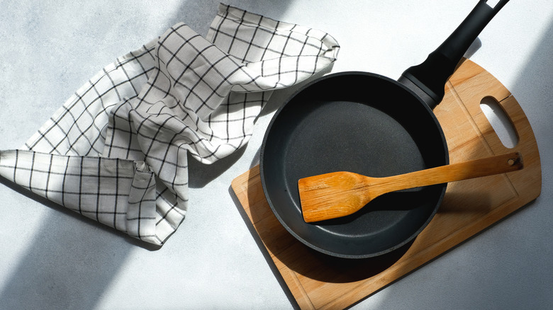 A clean cast iron pan with wooden spatula, cutting board, and serviette