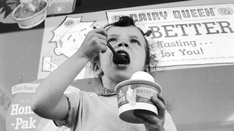 Young child eating ice cream outside Dairy Queen in 1955