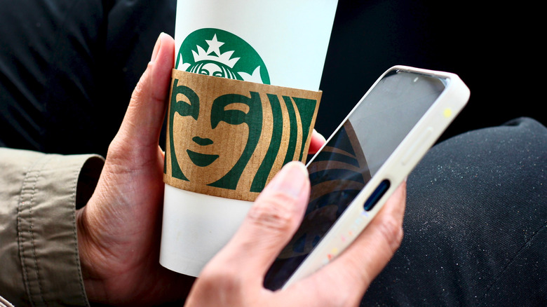 Hands holding starbucks cup and cellphone