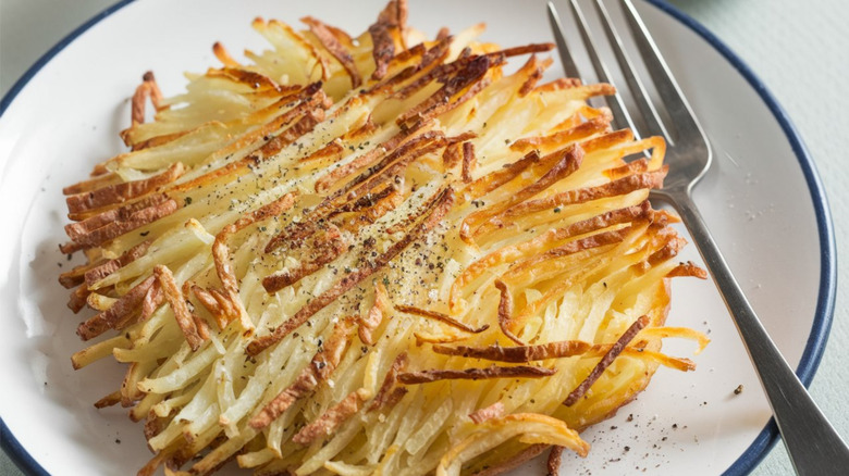 A plate of homemade hash browns served on a classic white plate with blue trim.