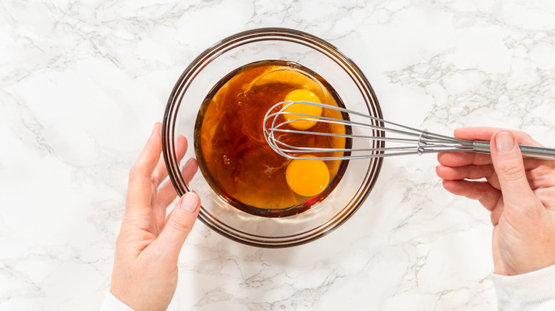 A baker whisking eggs and maple syrup together.