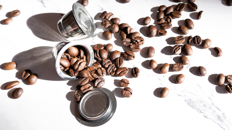 Reusable coffee pods with coffee beans on a marble countertop