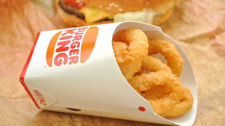 Onion rings in a Burger King container next to a burger