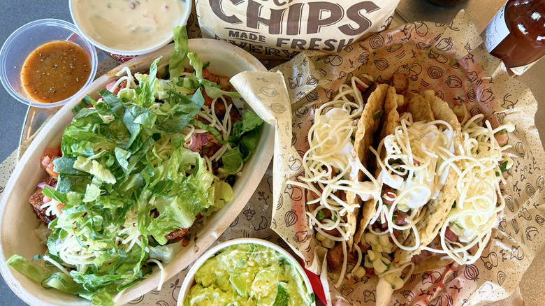 Chipotle burrito bowl and tacos with a hefty amount of toppings including cheese and lettuce