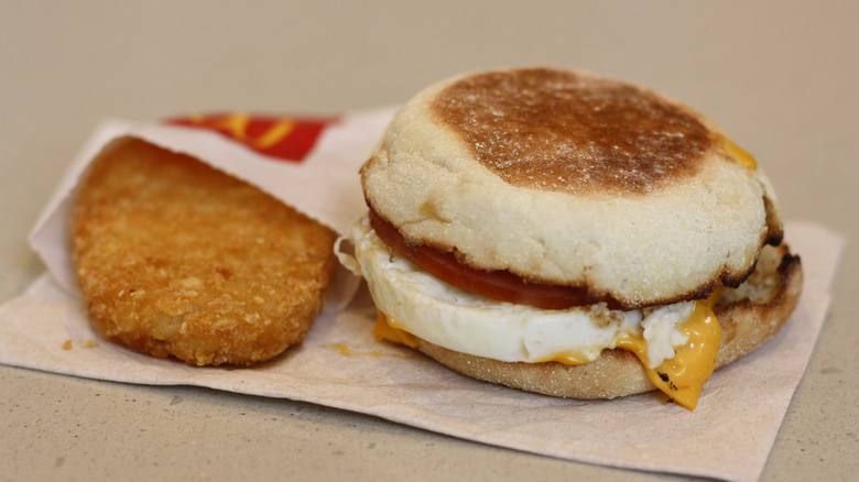 A McDonald's hash brown on a napkin beside an Egg McMuffin also from McDonald's