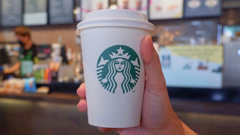 Hand holding a Starbucks coffee cup.