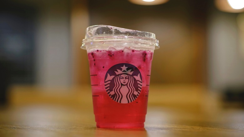A Dragonfruit Refresher from Starbucks sitting on a wooden surface.