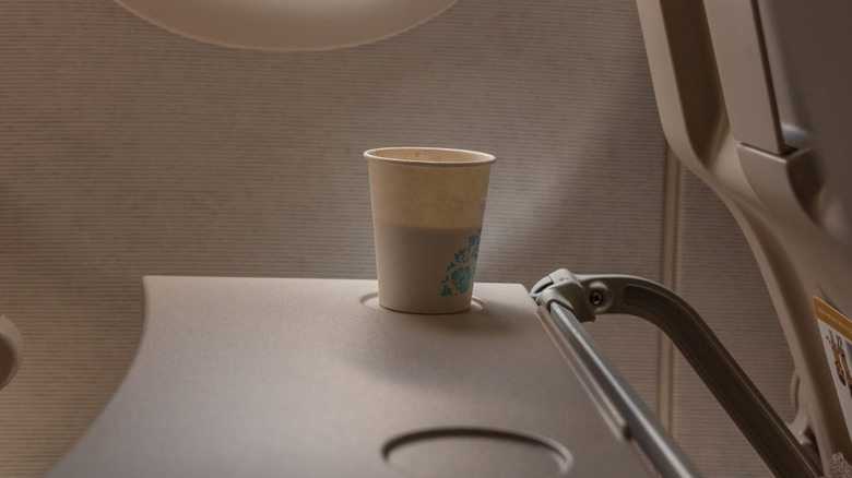 paper cup of coffee on airplane seat tray