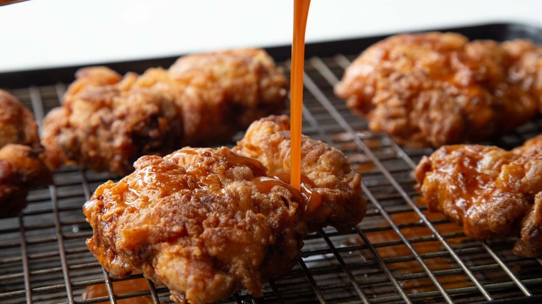 red sauce being poured on a fried chicken strip
