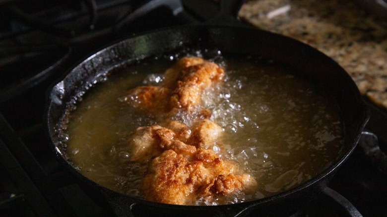 chicken strips frying in a black pan