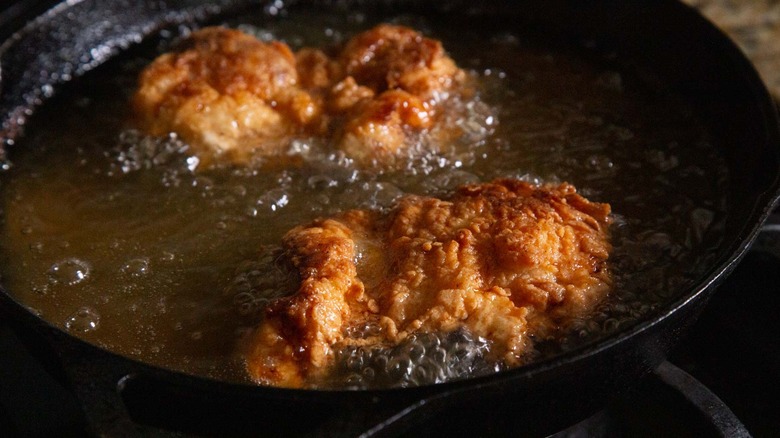 chicken strips frying in a black pan