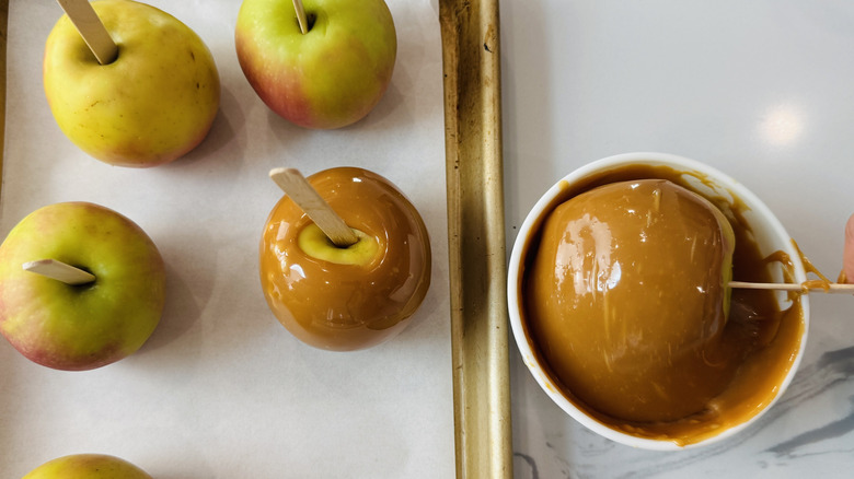 Dipping apples into caramel