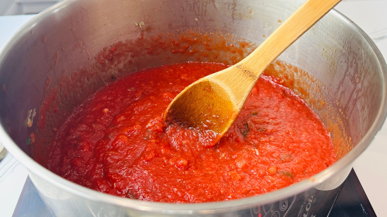 Crushed tomatoes and wooden spoon in pot