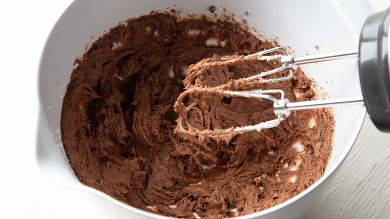 chocolate frosting in a white bowl with a mixer