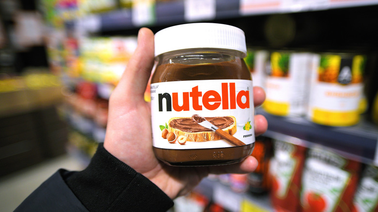 Hand holding a jar of Nutella