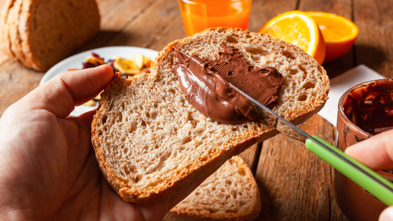 Hands spreading chocolate spread on bread