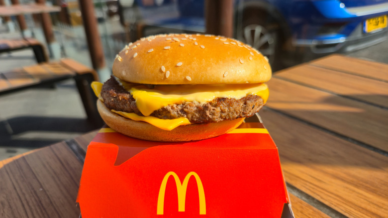 A Mcdonald's quarter pounder placed atop its cardboard packaging