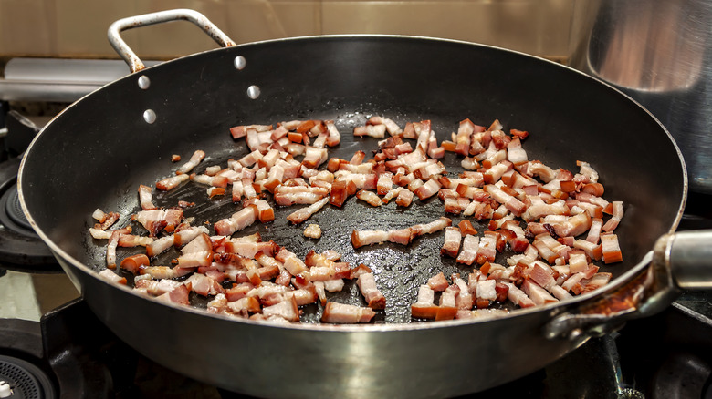 Chopped bacon bits frying in a skillet