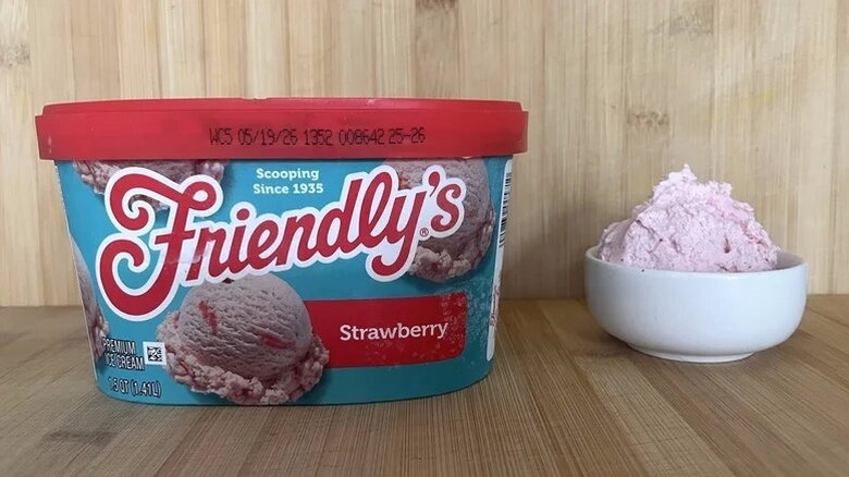 A tub of Friendly's strawberry ice cream, next to a bowl with a scoop in it.