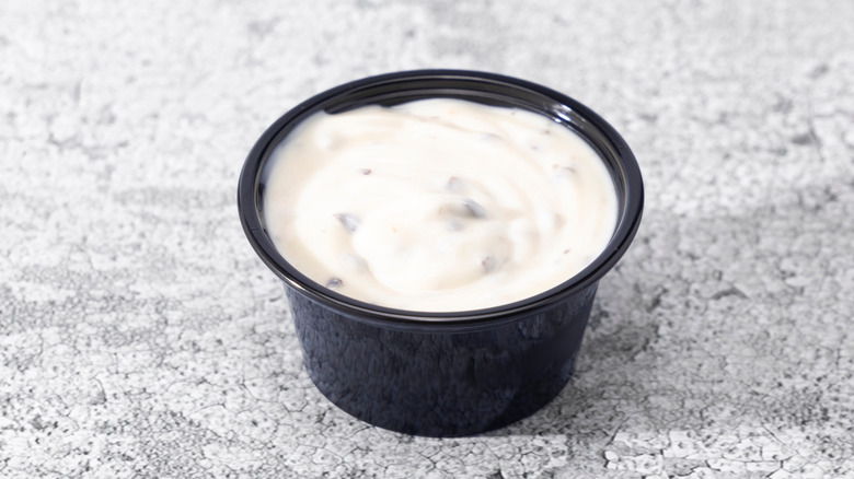 Small plastic condiment cup of ranch dressing