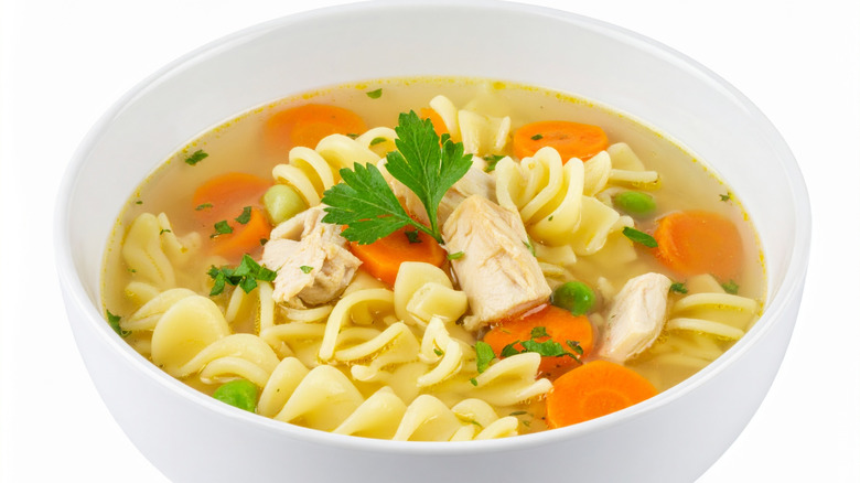 A bowl of chicken noodle soup with pieces of chicken and vegetables