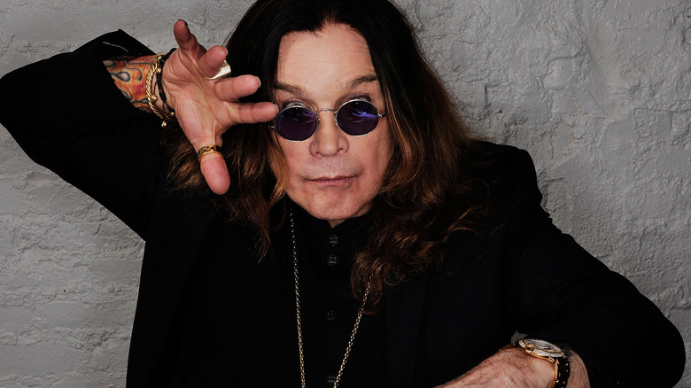 Ozzy Osbourne poses in his signature round sunglasses at an event