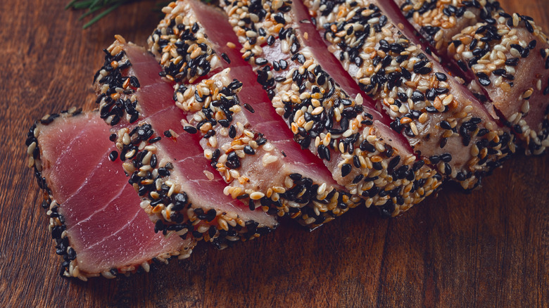 Sesame seed encrusted tuna steak on cutting board sliced