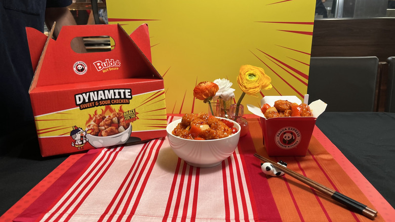 A bowl of Panda Express dynamite sweet and sour chicken with a box and chop sticks