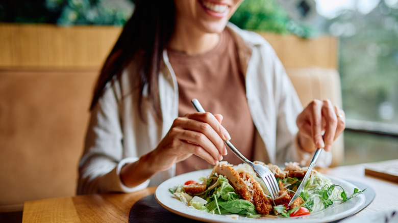 A woman eating a chicken salad at a restaurant.