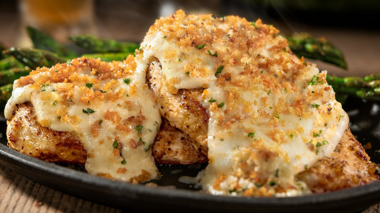 parmesan crusted chicken on a black plate with asparagus.