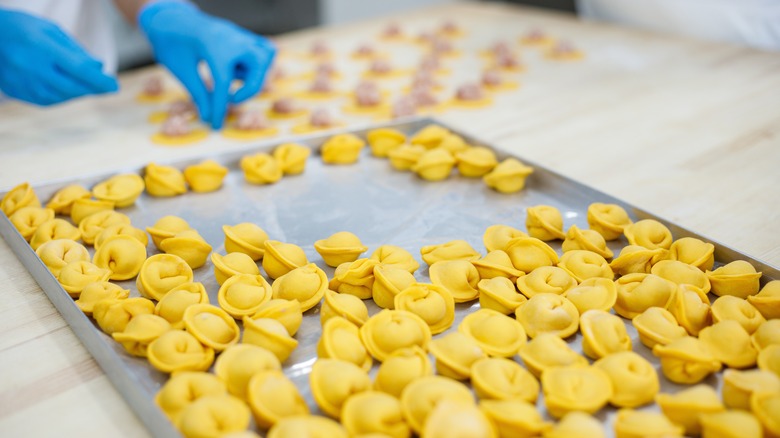 Gloved hands making filled pasta