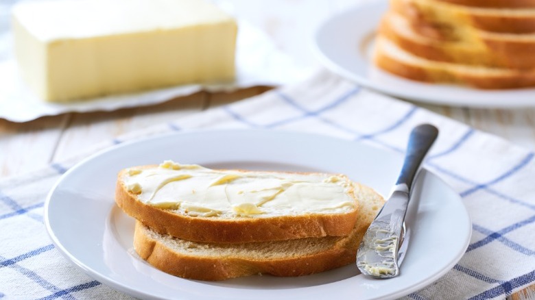Bread and butter on a plate at a table