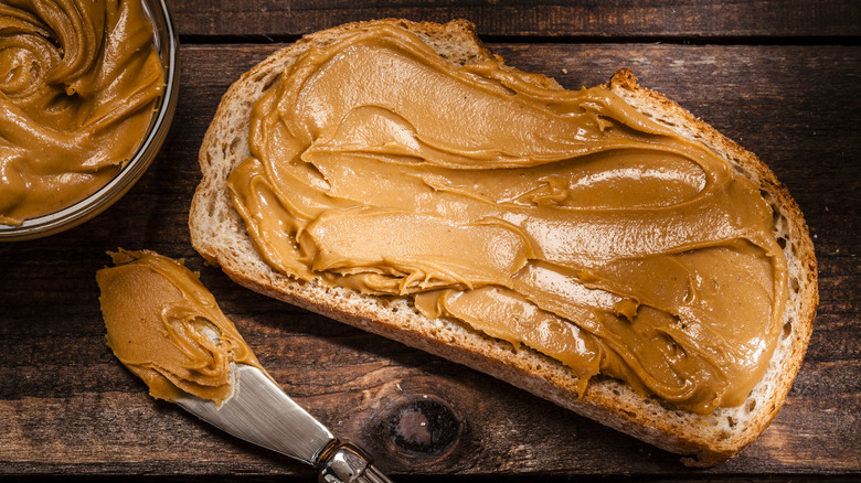 piece of whole grain bead with peanut butter slathered on it near a knife with the remains