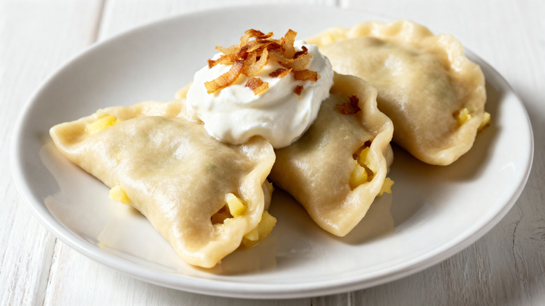 plate of potato pierogies with sour cream and onion