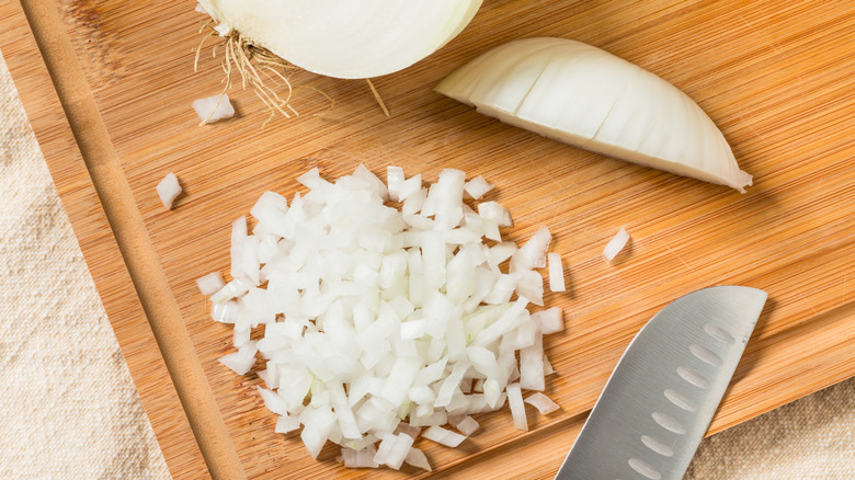 Chopped onions and knife on a wooden cutting board