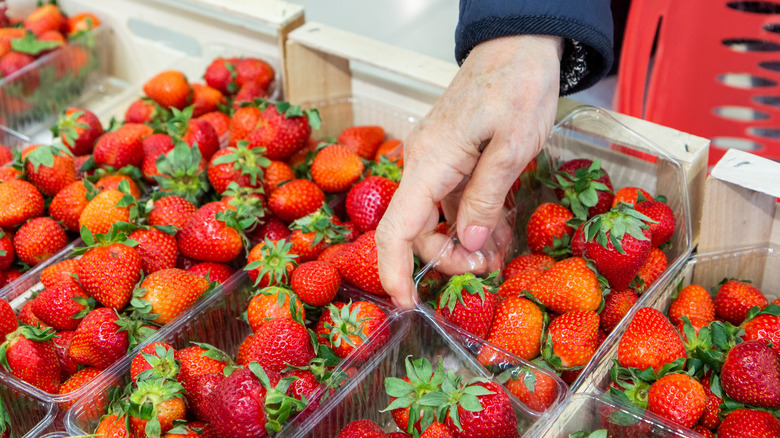 woman picking container of strawberries at the supermarket