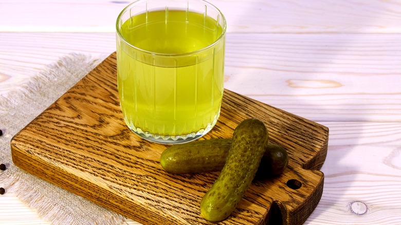 A glass of pickle brine with two pickles