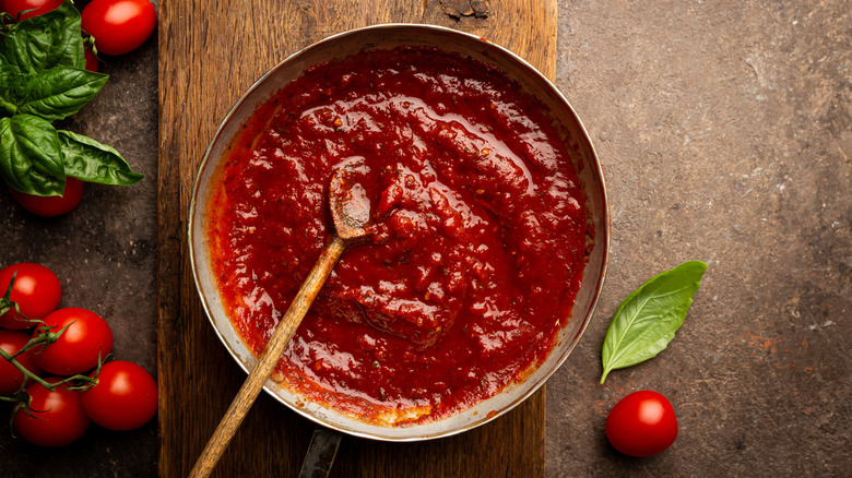 pizza sauce in a metal bowl with a wooden spoon