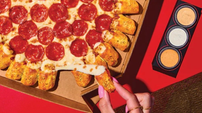 A hand tearing a cheesy bite off of a Cheesy Bite Pizza from Pizza Hut.