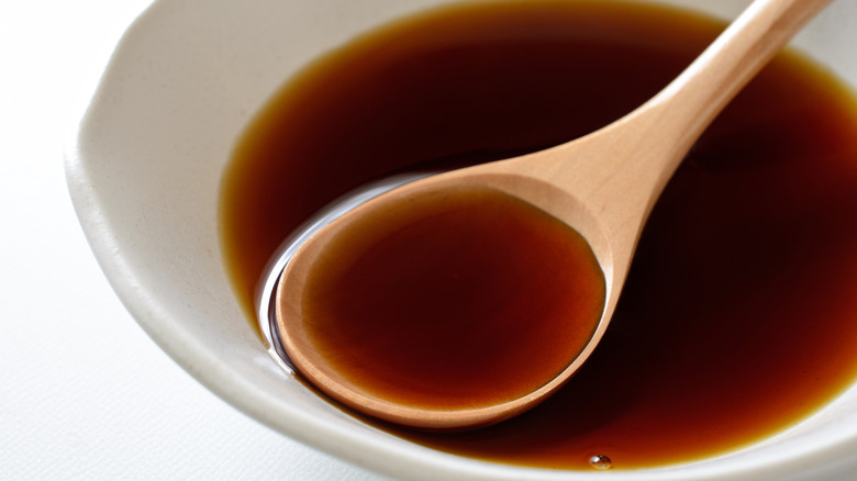 a white dish of ponzu sauce with a large wooden spoon in it