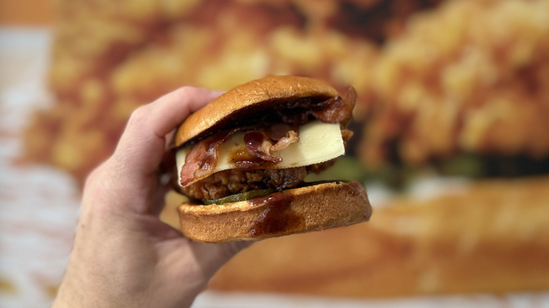 Popeyes' Honey BBQ Chicken Sandwich with Bacon and Cheese in hand