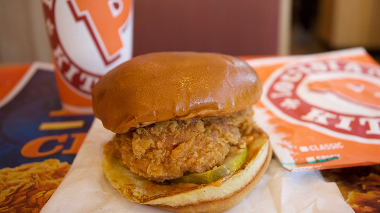 Popeyes chicken sandwich with drink in the background