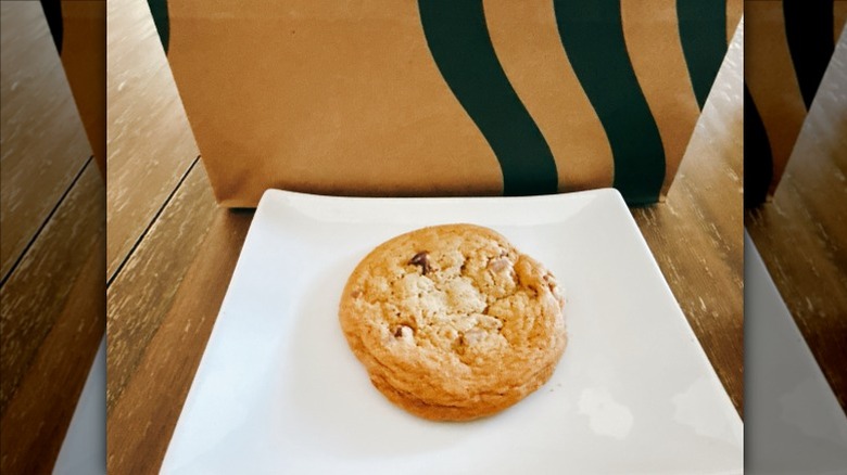 Starbucks Chocolate Chip Cookie on a white plate with Starbucks bag in the background
