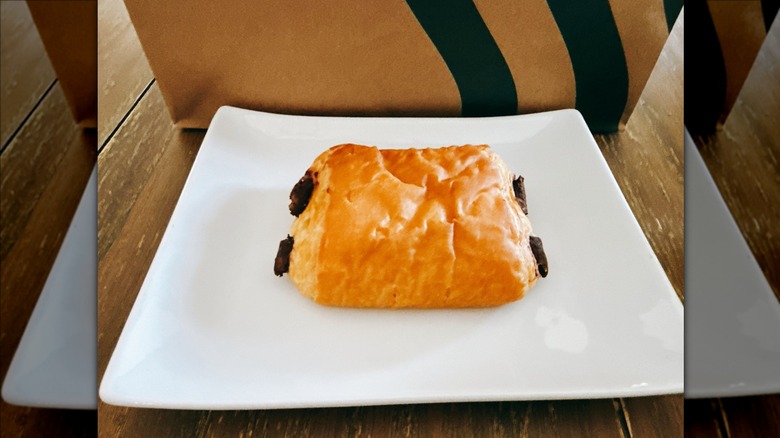 Starbucks Chocolate Croissant on a white plate with Starbucks bag in the background