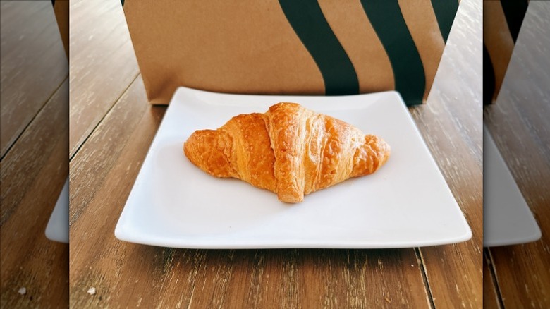 Starbucks Butter Croissant on a white plate with Starbucks bag in the background