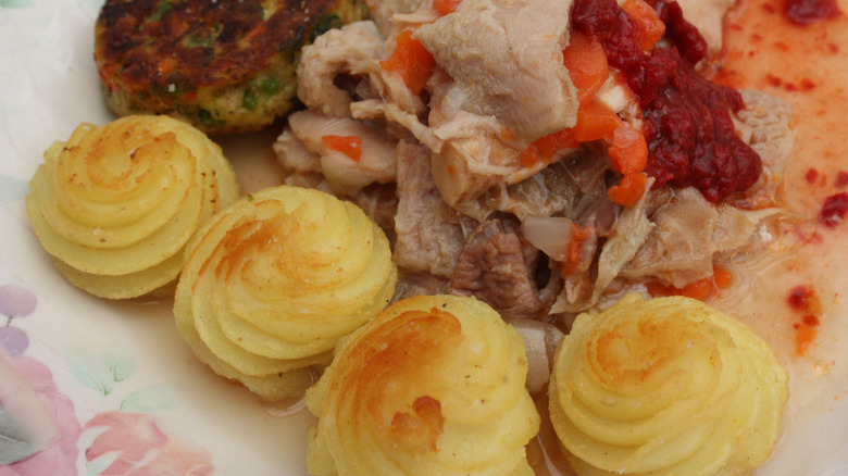 Golden piped Duchess potatoes on plate with meat