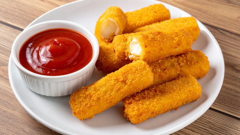 Fried mozzarella sticks, served with ramekin of catsup on white plate