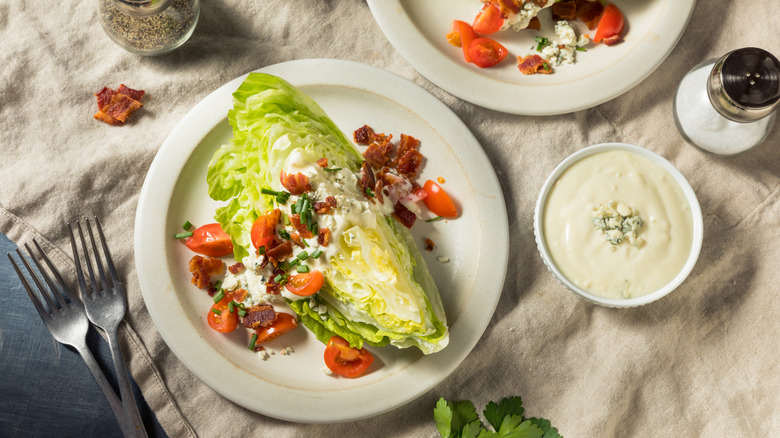 Top-down shot of wedge salad on white plate, beige tablecloth