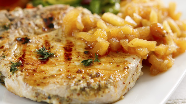 A pork chop with applesauce on a plate