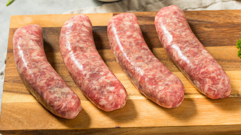 Raw sausages on a wooden board